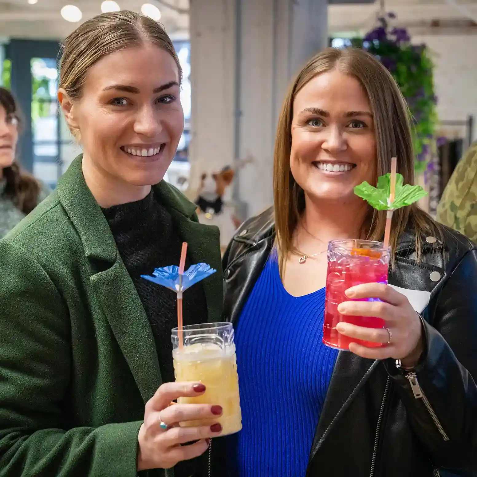 Two smiling female guests with umbrella drinks at a Tipsy Tiger catered event